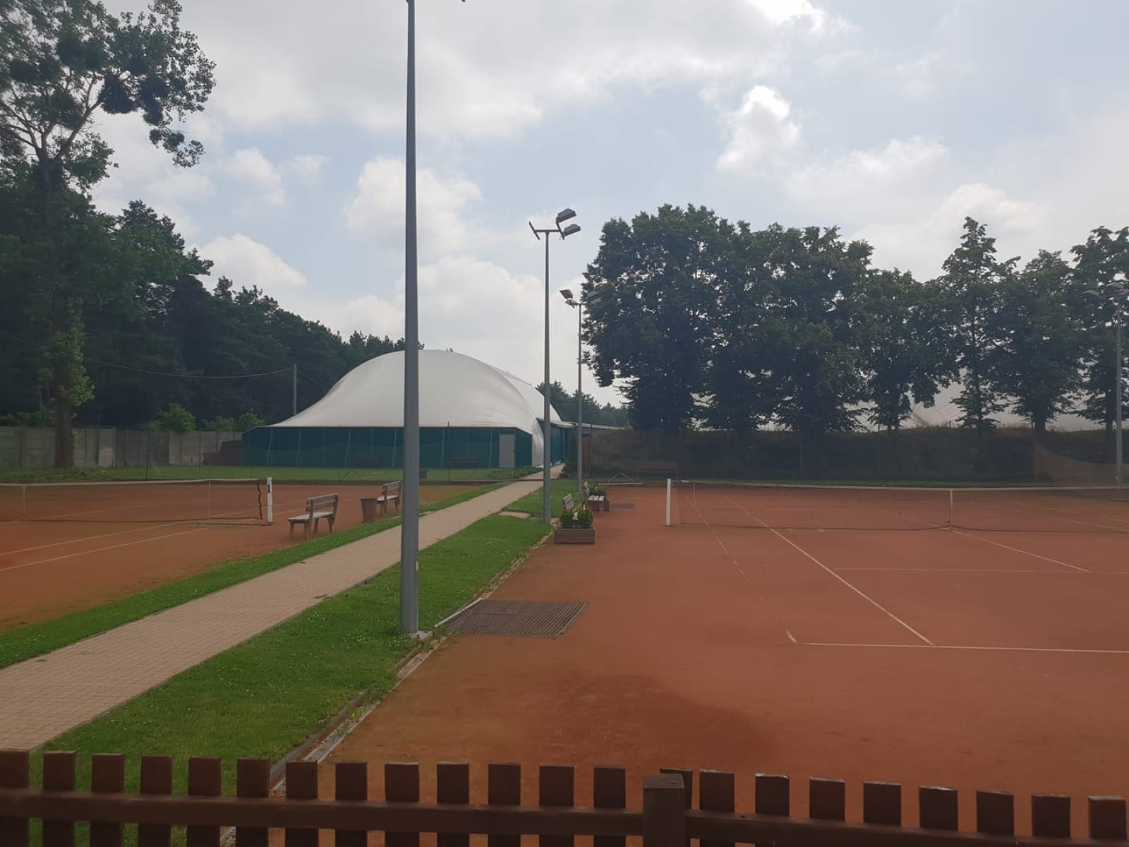Korty tenisowe Vamos w Otwocku - dwa korty z czerwonej mączki i hala balonowa w tle